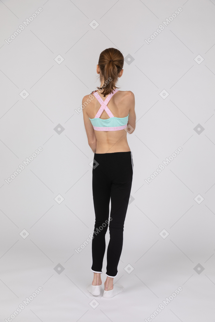 Vista traseira de uma adolescente em roupas esportivas, parada