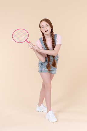 Optimistic teenage girl holding tennis racket