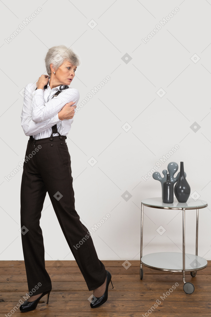 Front view of an old lady in office clothing embracing herself