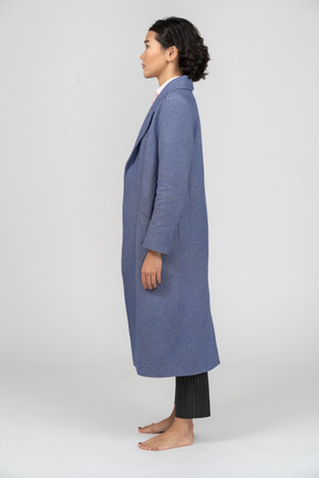 Vista lateral de uma mulher em pé de casaco azul