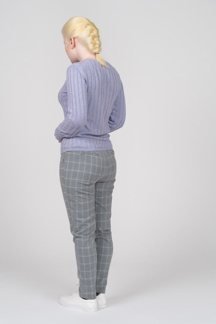 Three-quarter back view of a woman in casual clothes looking down