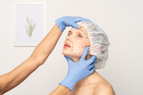 Mujer joven con gorra quirúrgica y manos inclinando la cabeza