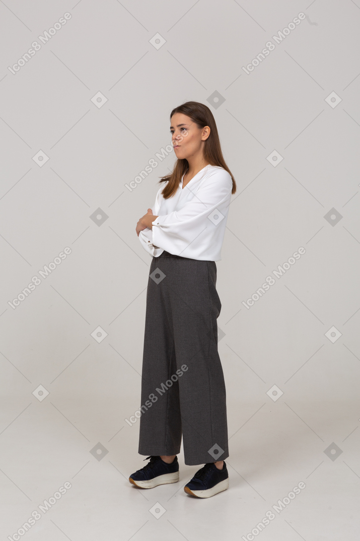 Three-quarter view of a strict young lady in office clothing crossing arms
