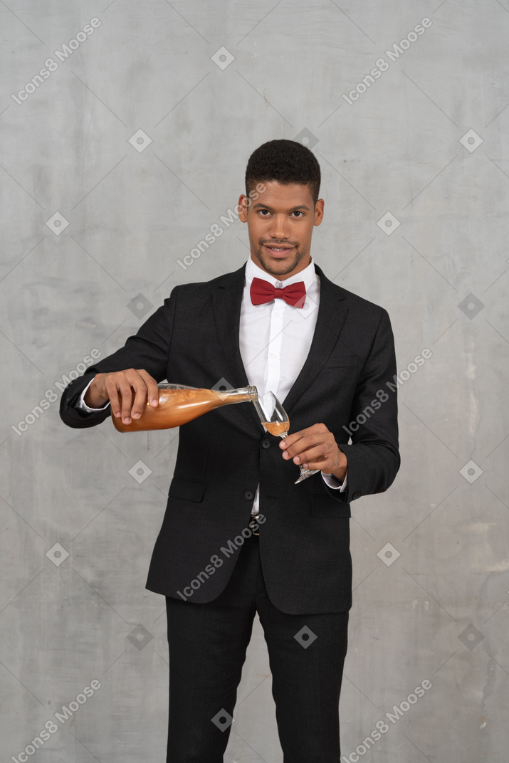 Man filling a champagne glass and looking at camera