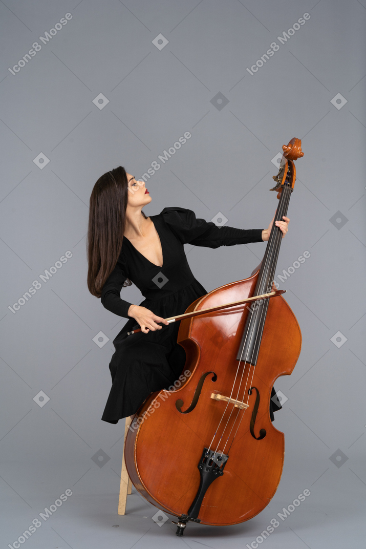 一位年轻的女士，坐在一把椅子上，同时玩一把弓的低音提琴的前视图