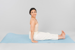 Young indian woman sitting with back straight on yoga mat