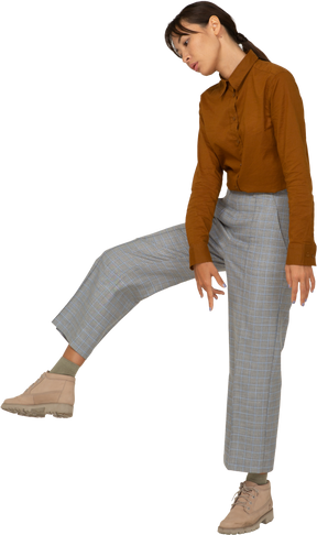 Vista frontal de una joven mujer asiática en calzones y blusa levantando la pierna
