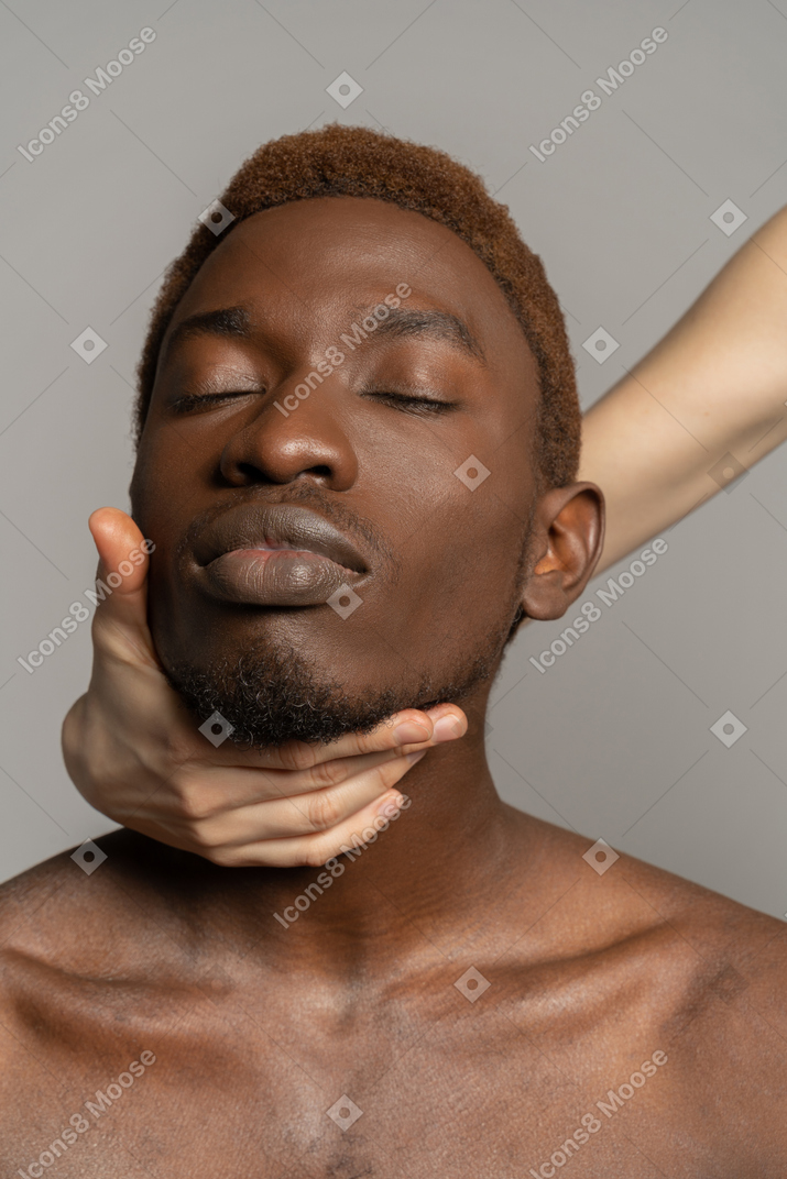 Белая рука держит шею молодого черного человека