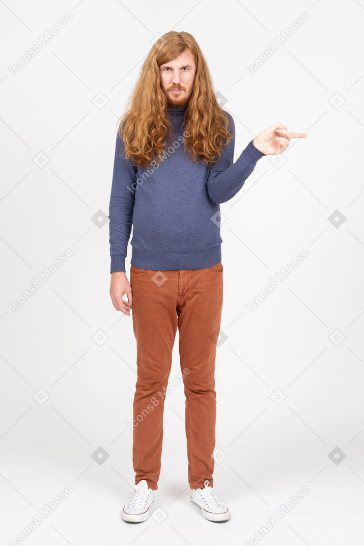 Vorderansicht eines jungen mannes in freizeitkleidung, der mit dem finger zeigt