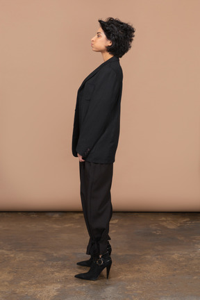 Vista laterale di una donna d'affari in un abito nero imbronciato e guardando da parte