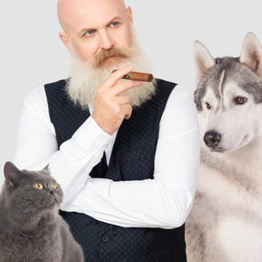A man smoking a cigar next to a dog and a cat