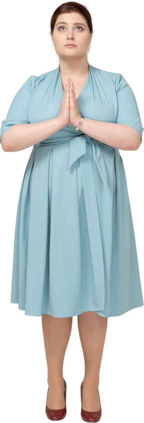 기도하는 제스처를 만드는 파란 드레스에 여자의 전면 보기