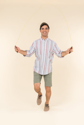 Excited looking young caucasian man jumping over jump rope