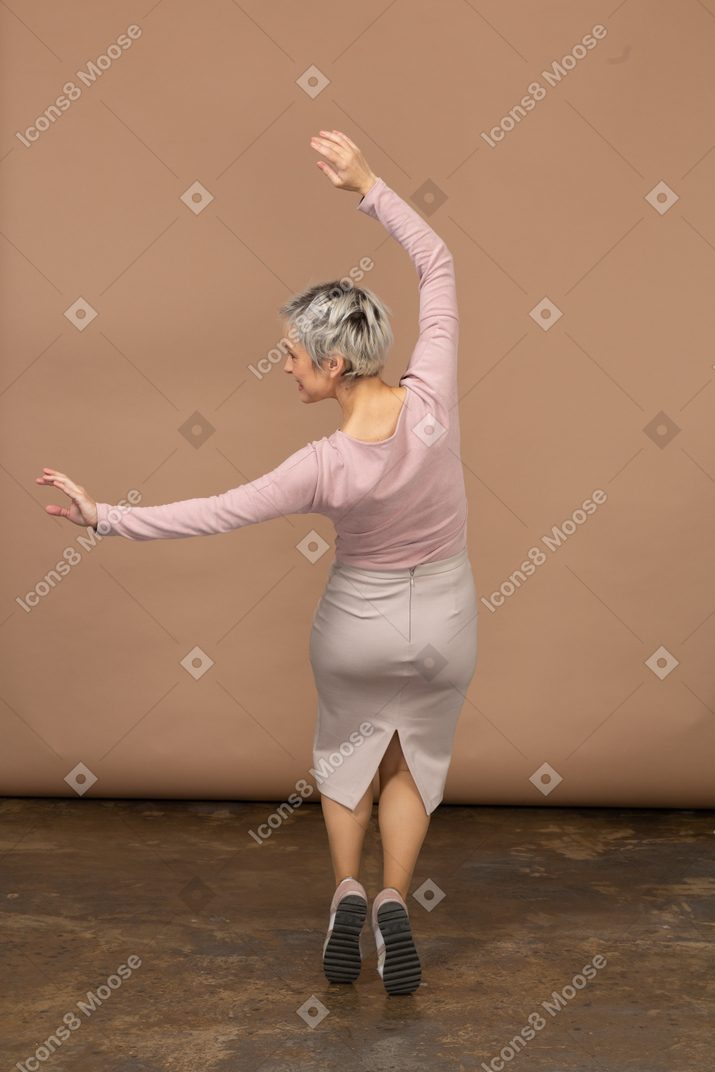 Vista posteriore di una donna in abiti casual in piedi sulle punte dei piedi
