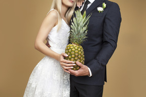 Bride and groom hugging and holding a pineapple