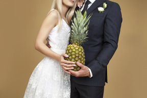 Sposa e sposo che abbraccia e che tiene un ananas