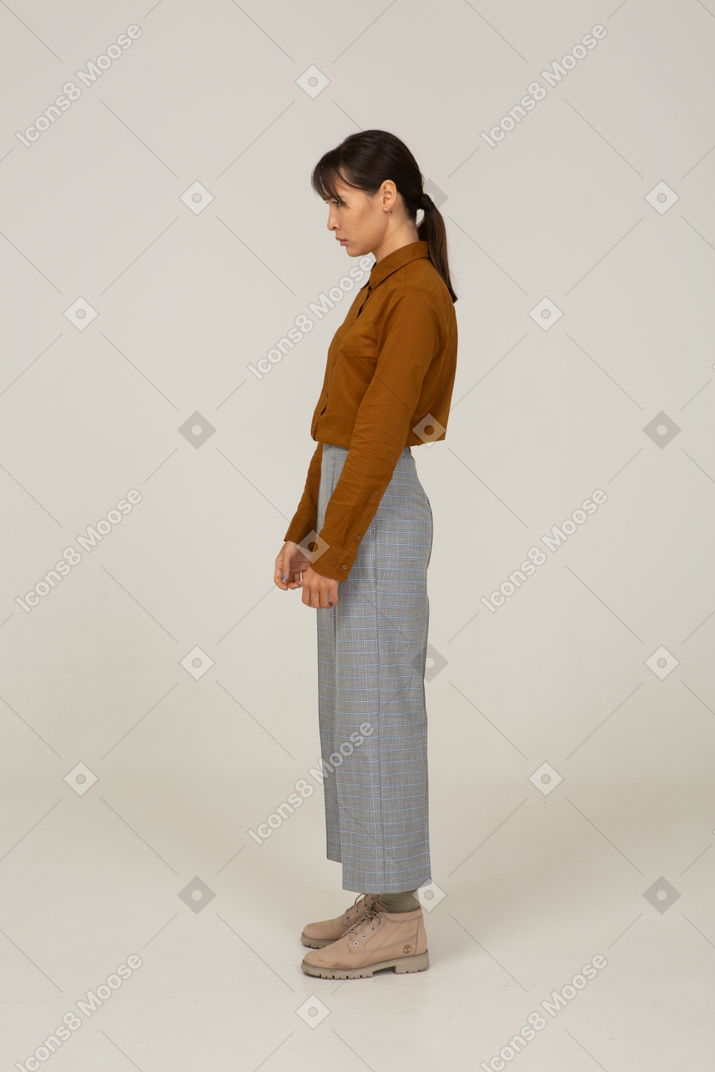 Вид сбоку расстроенной молодой азиатской женщины в бриджах и блузке