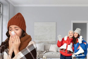 Woman blowing her nose next to two female friends