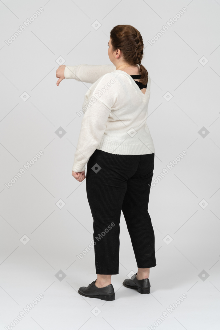 Plus size woman in white sweater showing thumb down