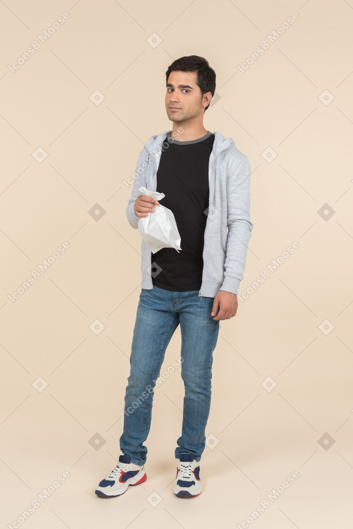 Молодой кавказский мужчина держит бумажный пакет