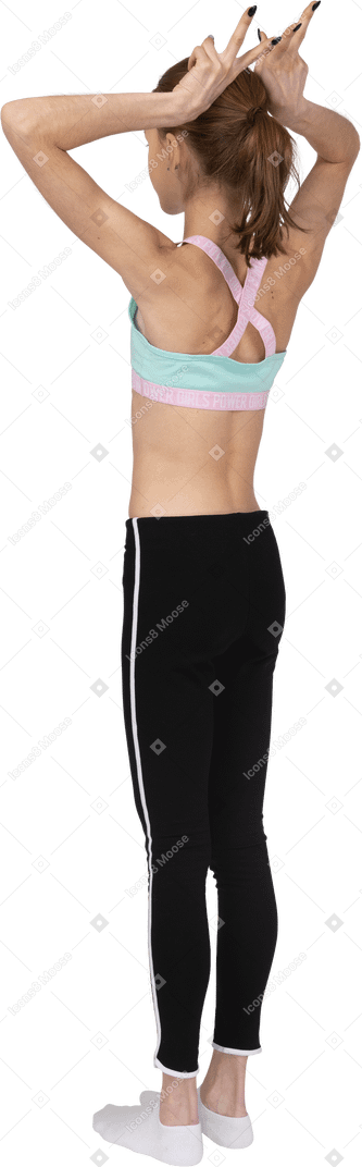 Vista posterior de tres cuartos de una jovencita en ropa deportiva haciendo cuernos