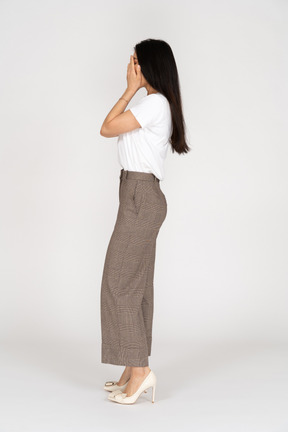 Side view of a young lady in breeches and t-shirt hiding her face