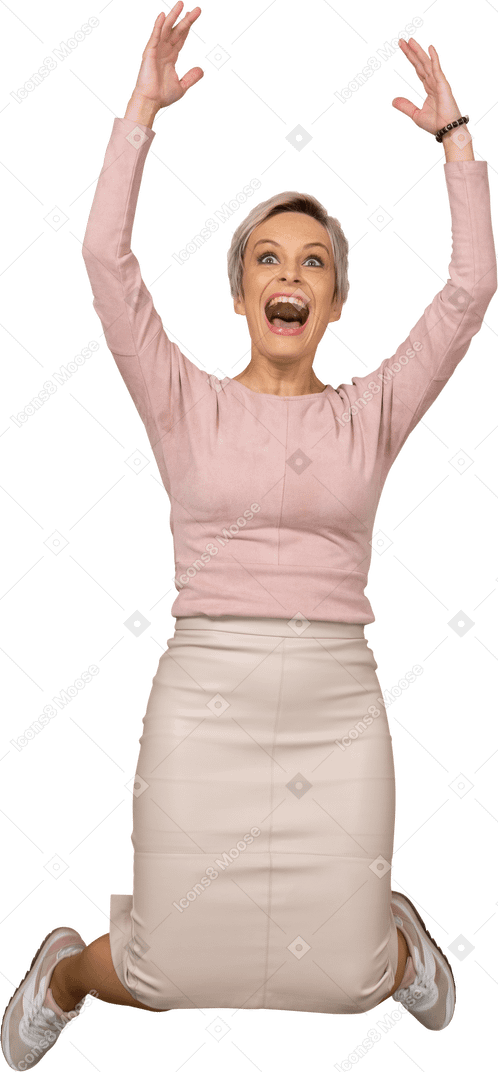 一个快乐的女人穿着休闲服，双臂高高跳跃的前视图