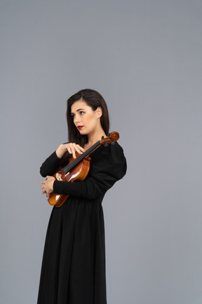 Three-quarter view of a young lady in black dress holding the violin