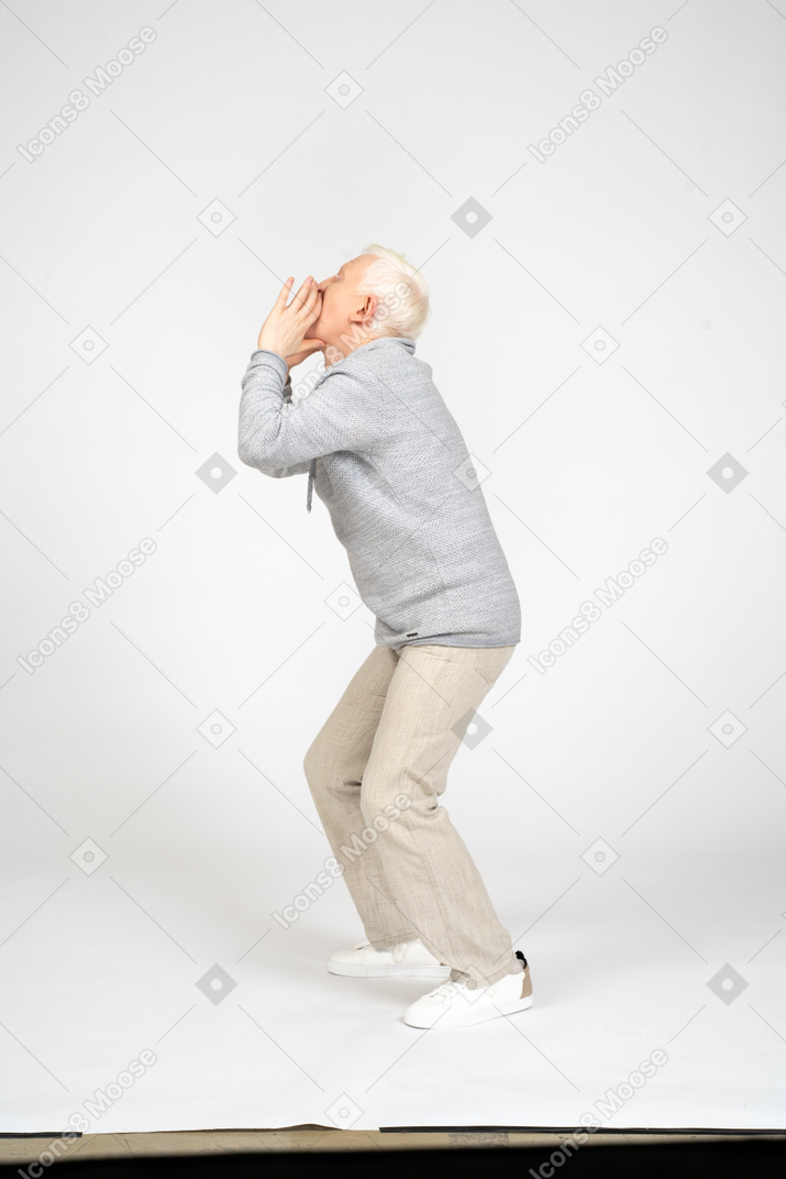Vista lateral de un hombre con las rodillas dobladas gritando