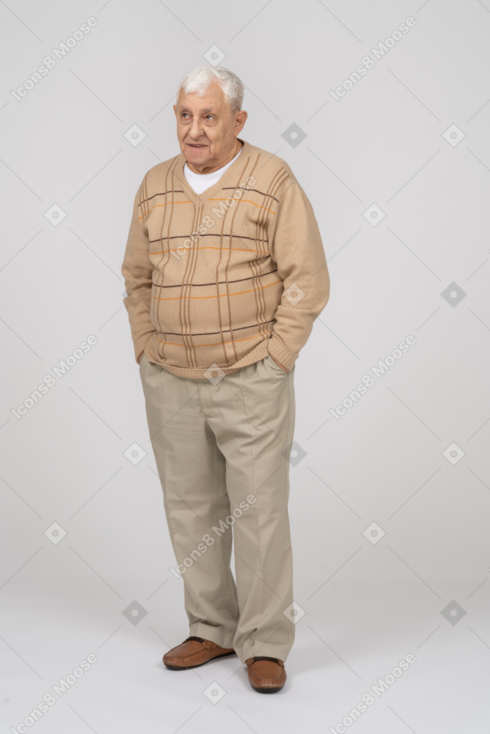 Vorderansicht eines alten mannes in freizeitkleidung, der mit den händen in den taschen steht