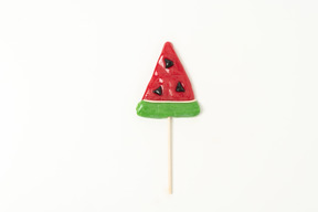 A red and green lollipop in a form of a piece of a watermelon, looking sweet and shiny