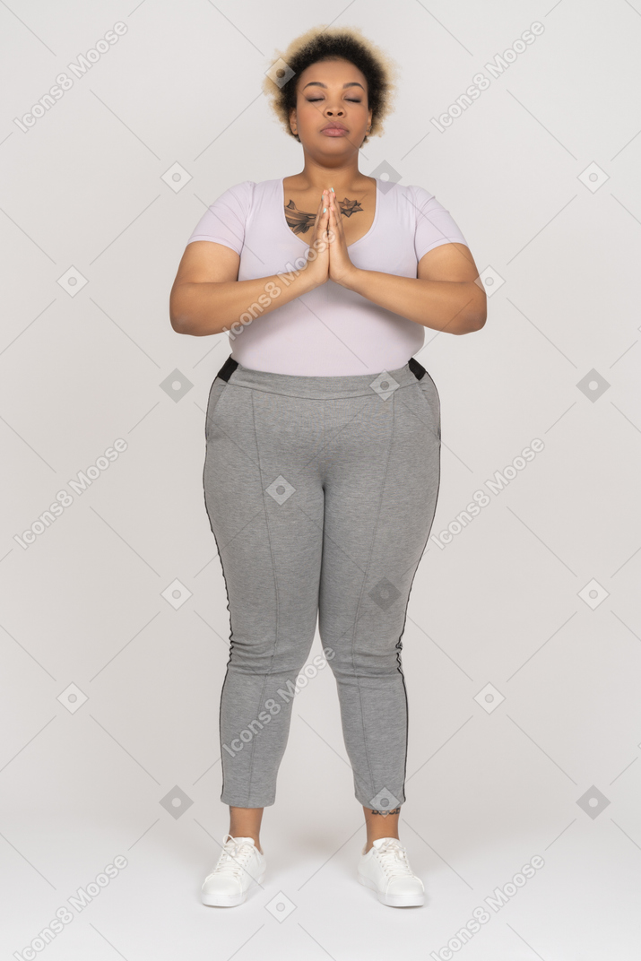 Corpo femmina nera positiva tenendo le mani insieme mentre medita con gli occhi chiusi