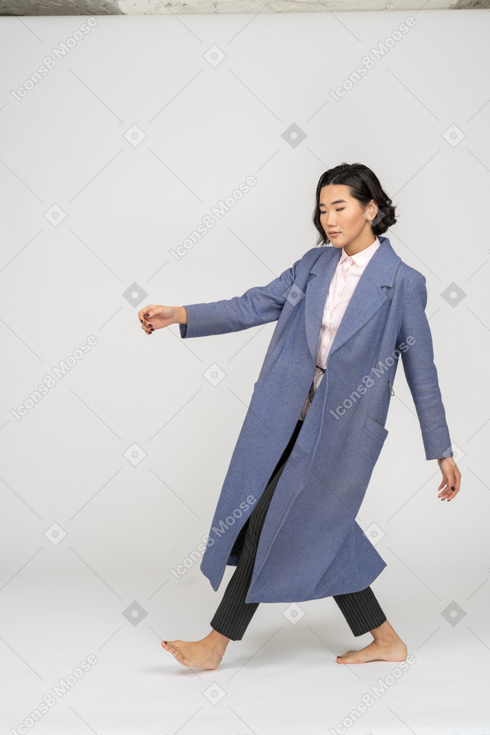 Woman in coat making step and leaning backwards