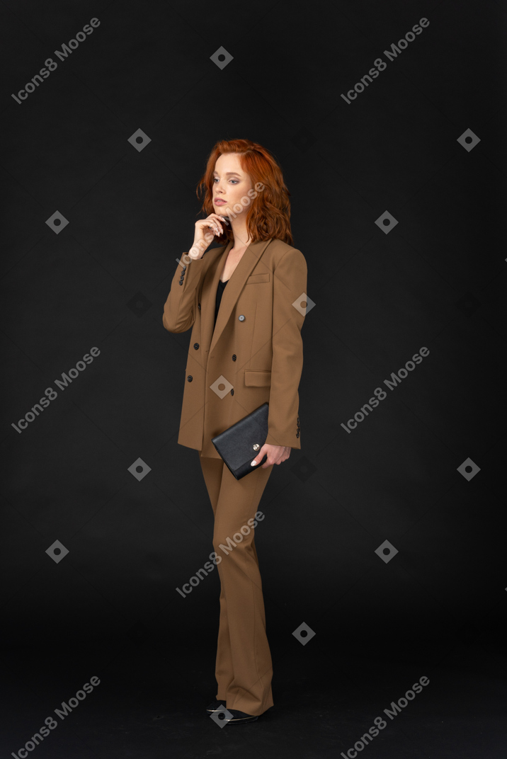 Pensive young formally dressed woman in suit holding bag