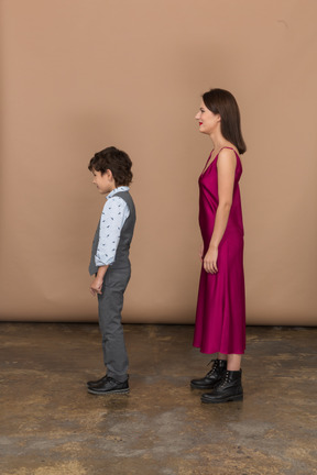 Femme en robe rouge et petit garçon debout de profil