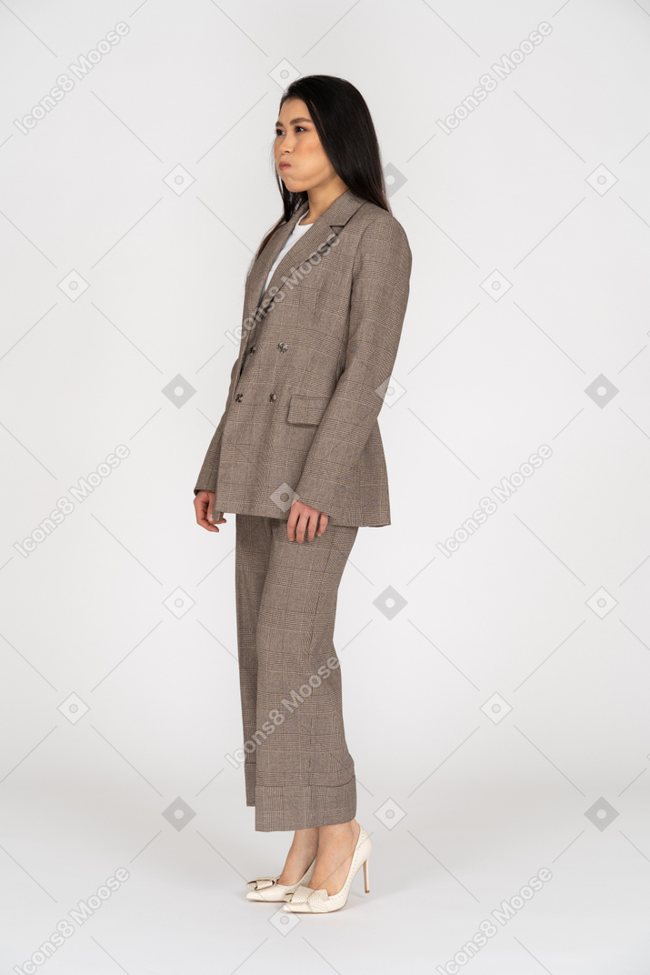 Вид в три четверти молодой леди в коричневом деловом костюме, надрывающей щеки