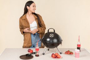 Young asian woman standing near closed grill on the table