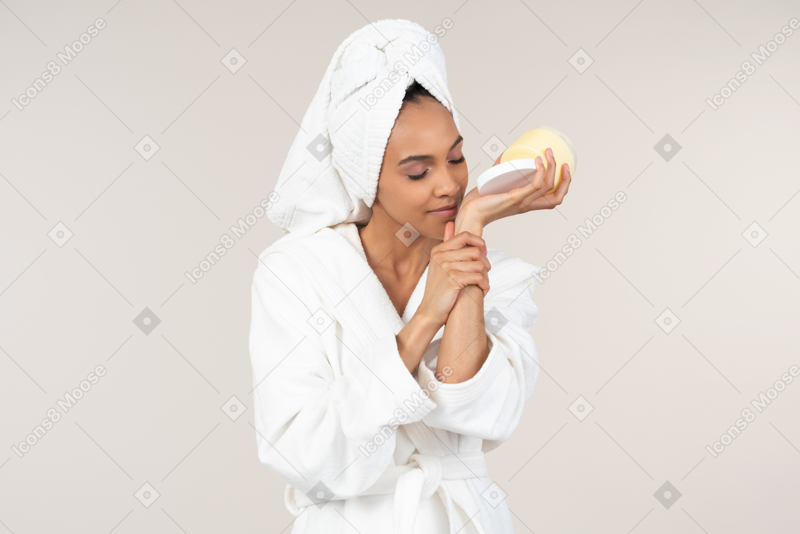 Black woman in white bathrobe and head towel enjoying her skin care routine
