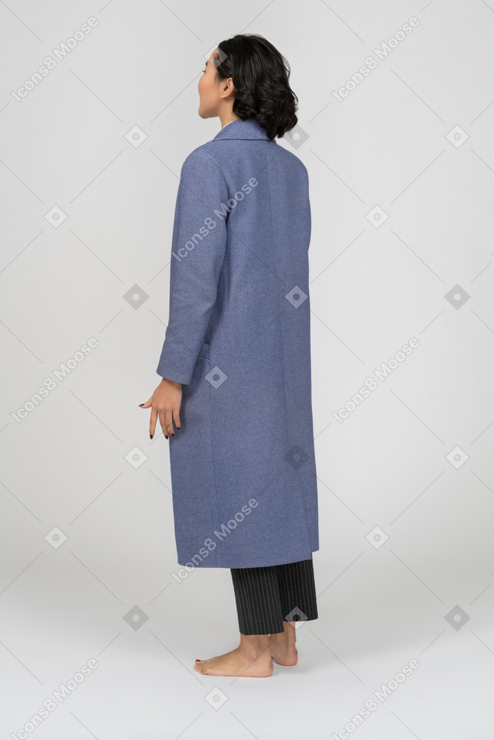 양 옆에 팔을 들고 서 있는 코트를 입은 여성의 뒷모습