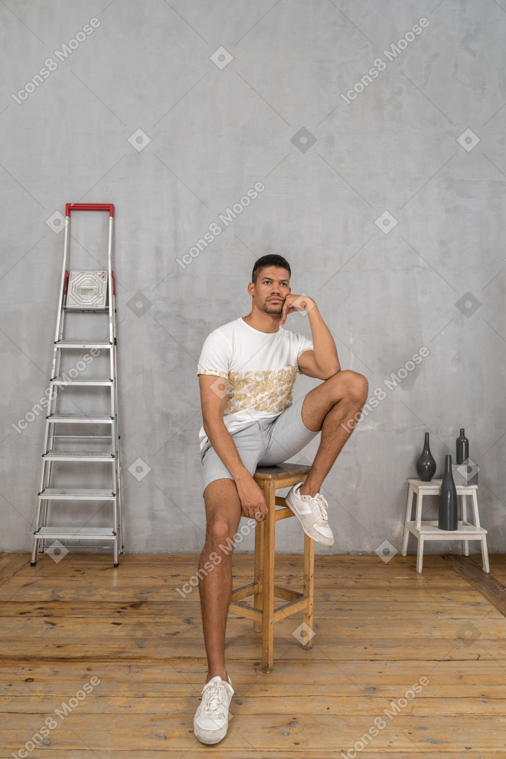 Молодой человек сидит на стуле и смотрит вверх