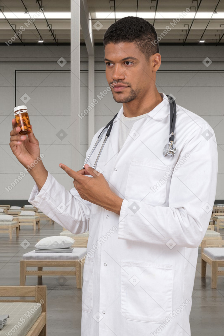 Médico segurando um frasco de comprimidos e apontando para ele