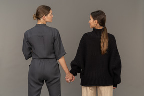 Back view of two women holding hands and looking at each other