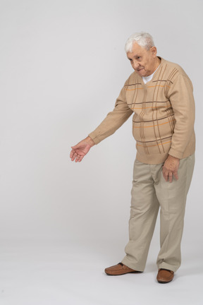 Front view of an old man in casual clothes standing with extended arm