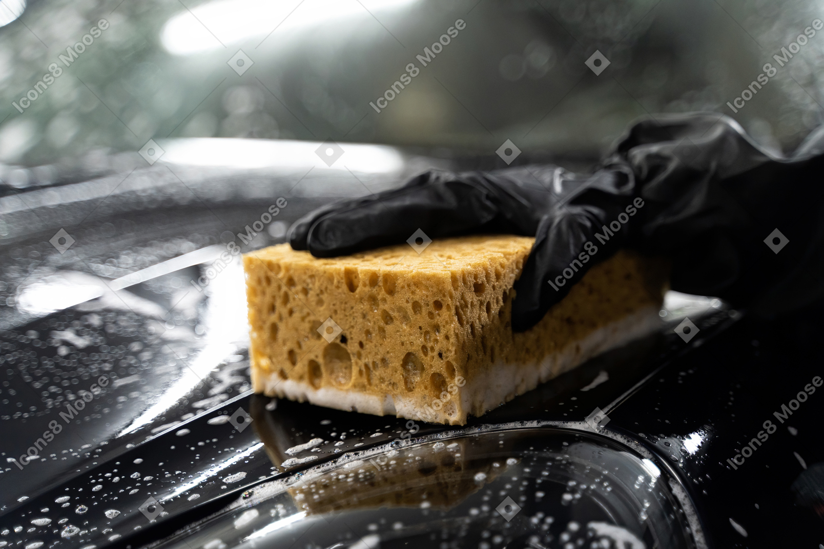 Human hand washing a car with sponge