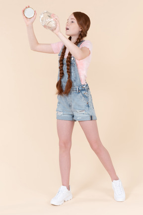 Surprised teenage girl looking at jar she's holding