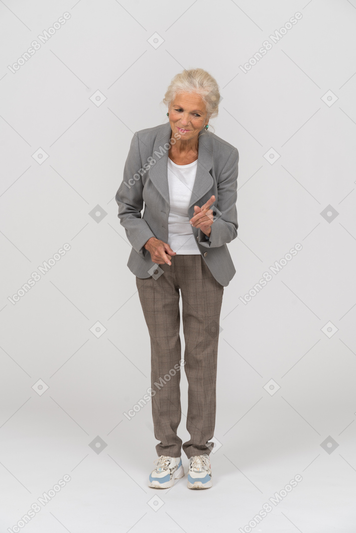 Vue de face d'une vieille dame en costume se penchant et montrant un panneau d'avertissement