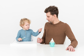 Vater bringt seinem kleinen sohn bei, wie man einen löffel benutzt