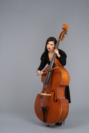 Three-quarter view of a bored young woman playing the double-bass