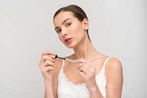 Beautiful young woman applying mascara