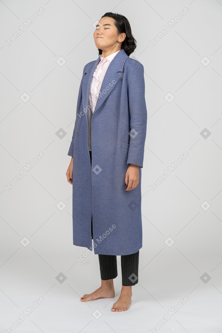 Woman in blue coat holding her breath with closed eyes